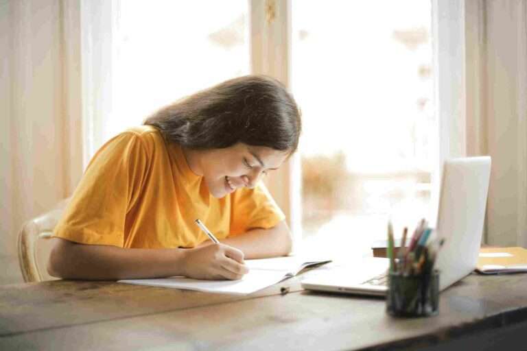 A school-girl is writing some on her book who kept on the table