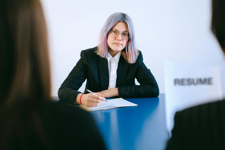 A girl, holding a pen and resting her hands on a book, looks ahead, seeking clarity and direction through career counseling for her future path.