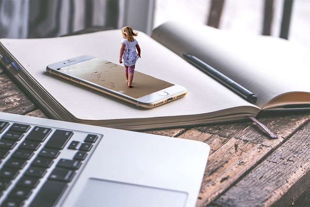 A single smartphone is placed on top of an accounting book, with a laptop positioned beside it, and an AI-generated small girl is walking across the screen of the smartphone.